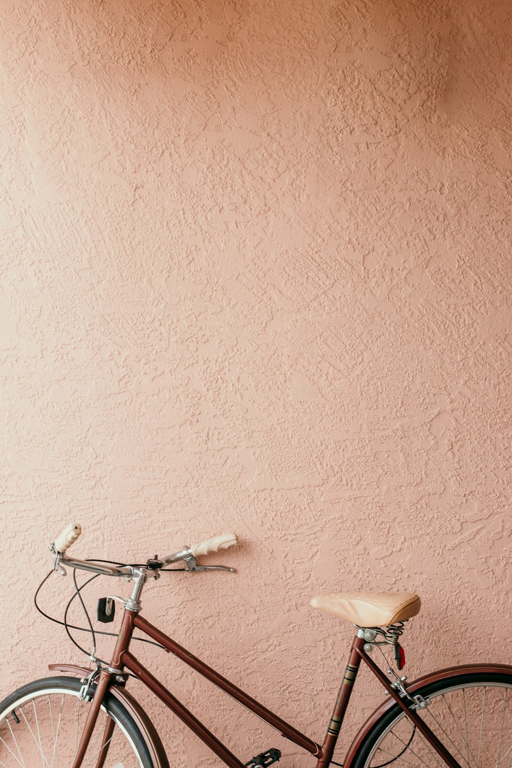 white city bike beside pink wall