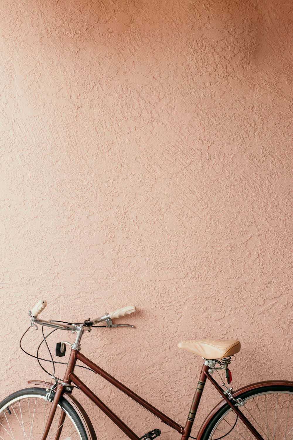 Bicicleta urbana blanca junto a la pared rosa