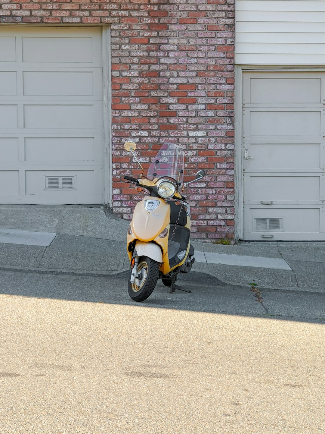 yellow and black motor scooter parked beside brown brick wall