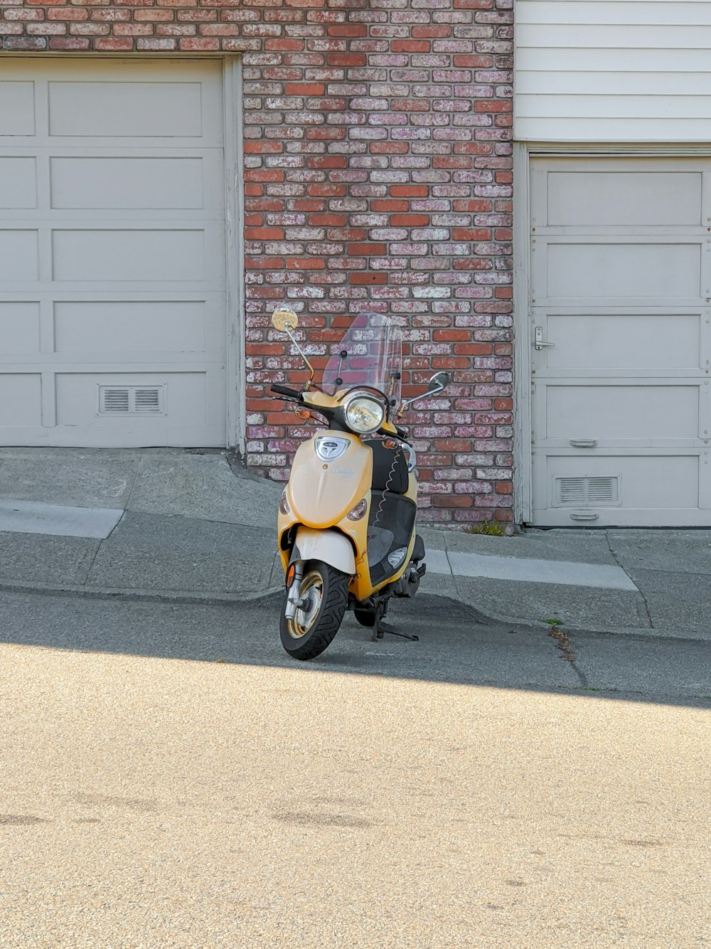 yellow and black motor scooter parked beside brown brick wall