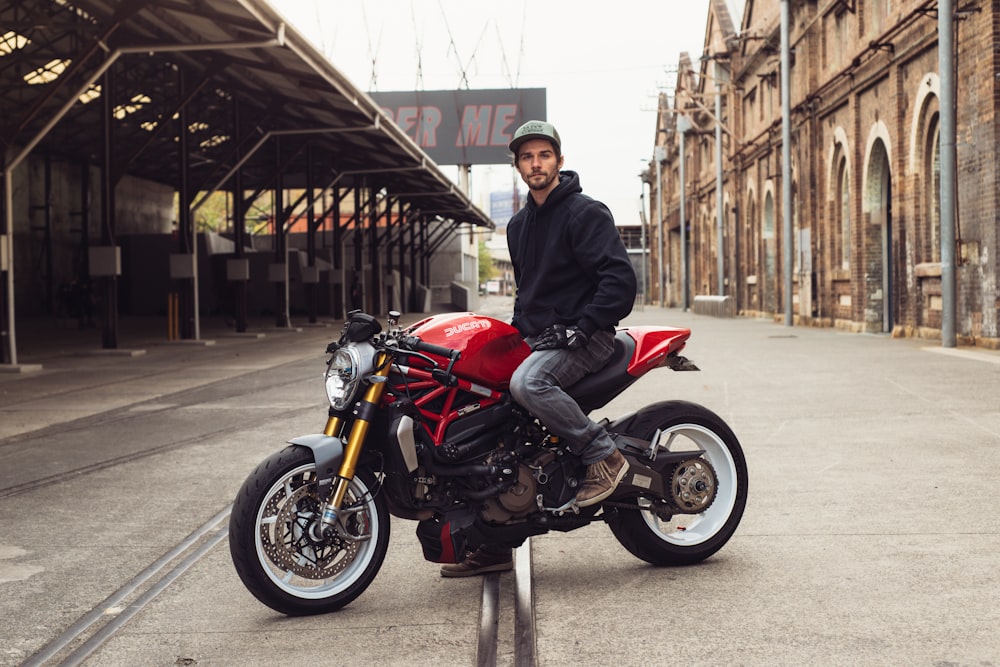 a man standing next to a red motorcycle