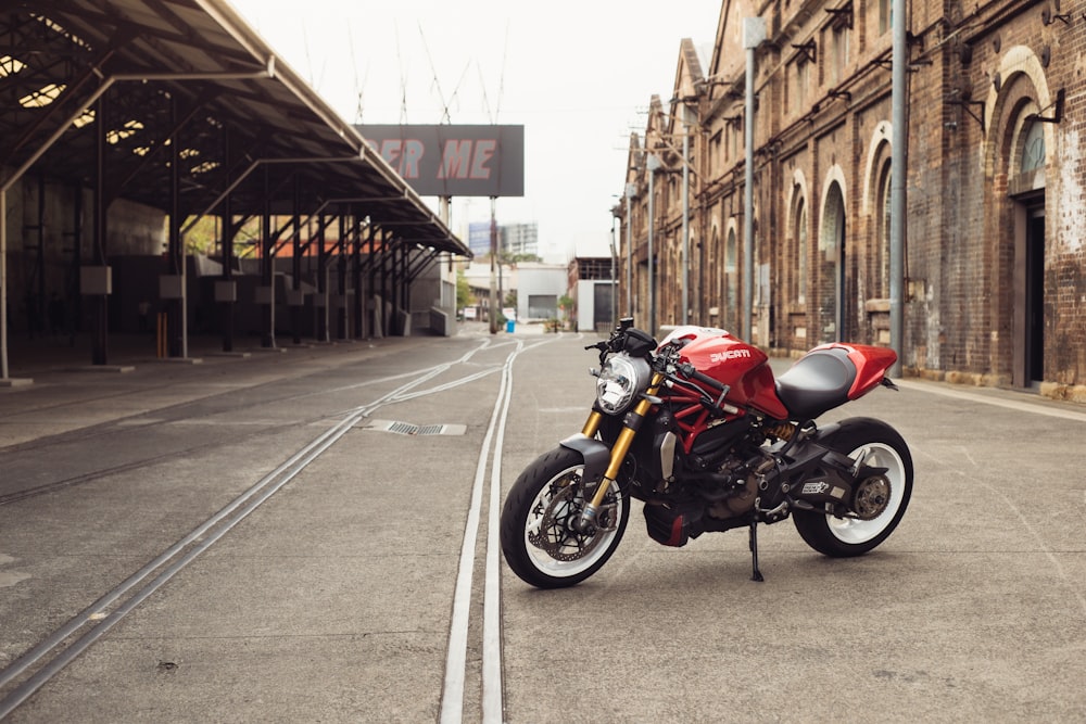 a red motorcycle parked in front of a train station