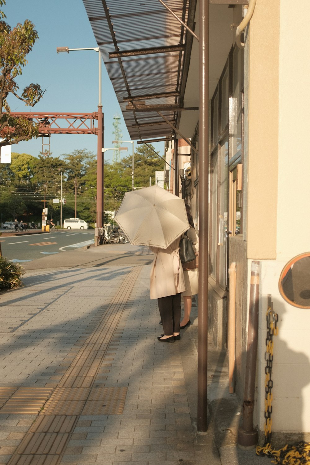 woman in black coat holding umbrella walking on sidewalk during daytime