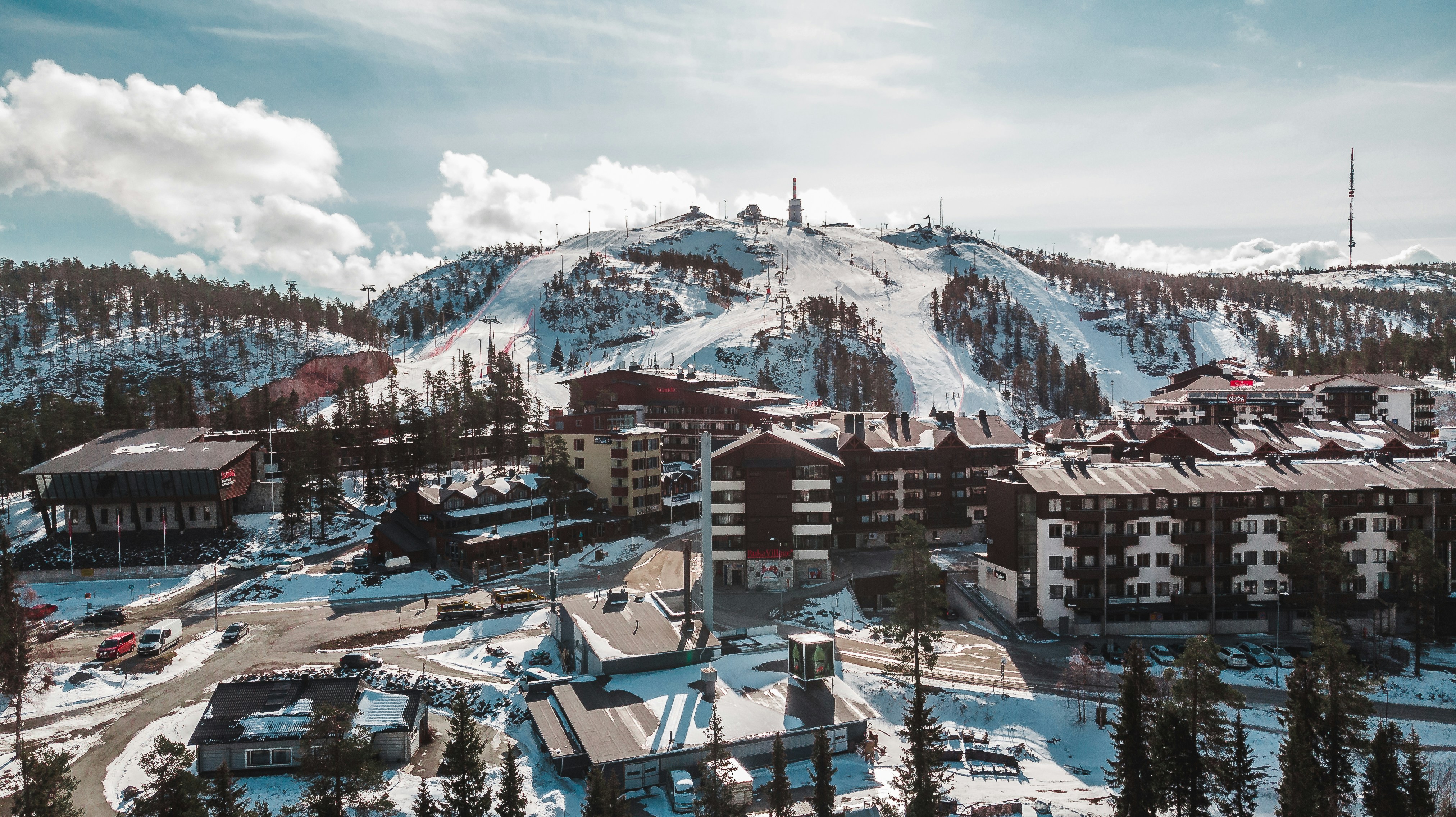 brown and white concrete buildings near snow covered mountain under white clouds and blue sky during