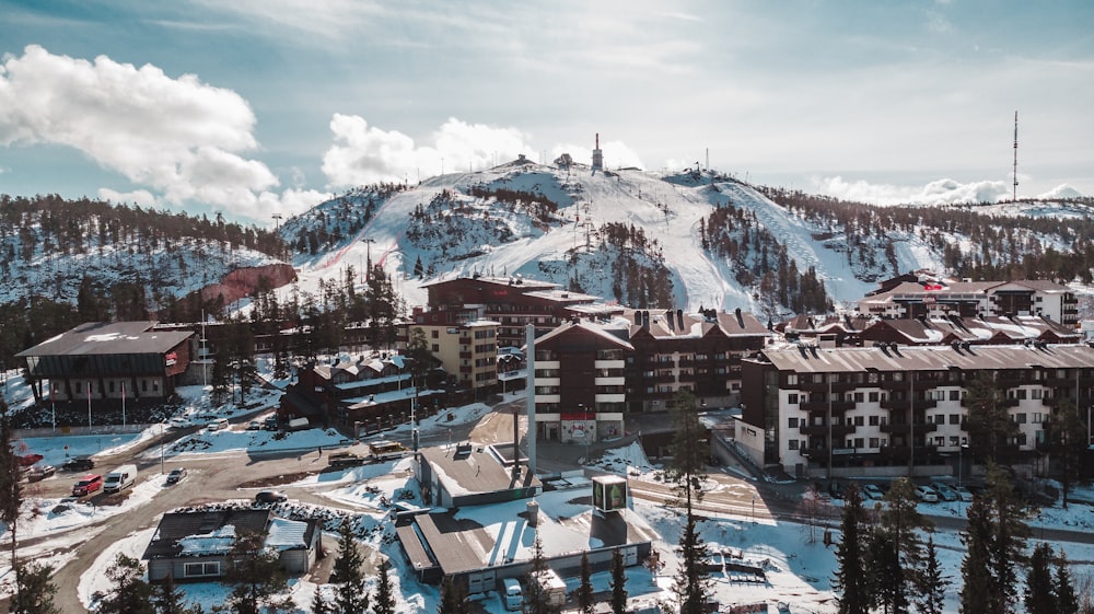 brown and white concrete buildings near snow covered mountain under white clouds and blue sky during