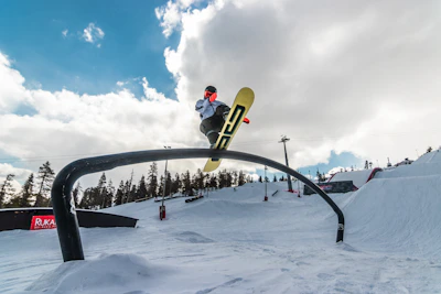 Young snowboarder practicing tricks on rails in a snowy park.