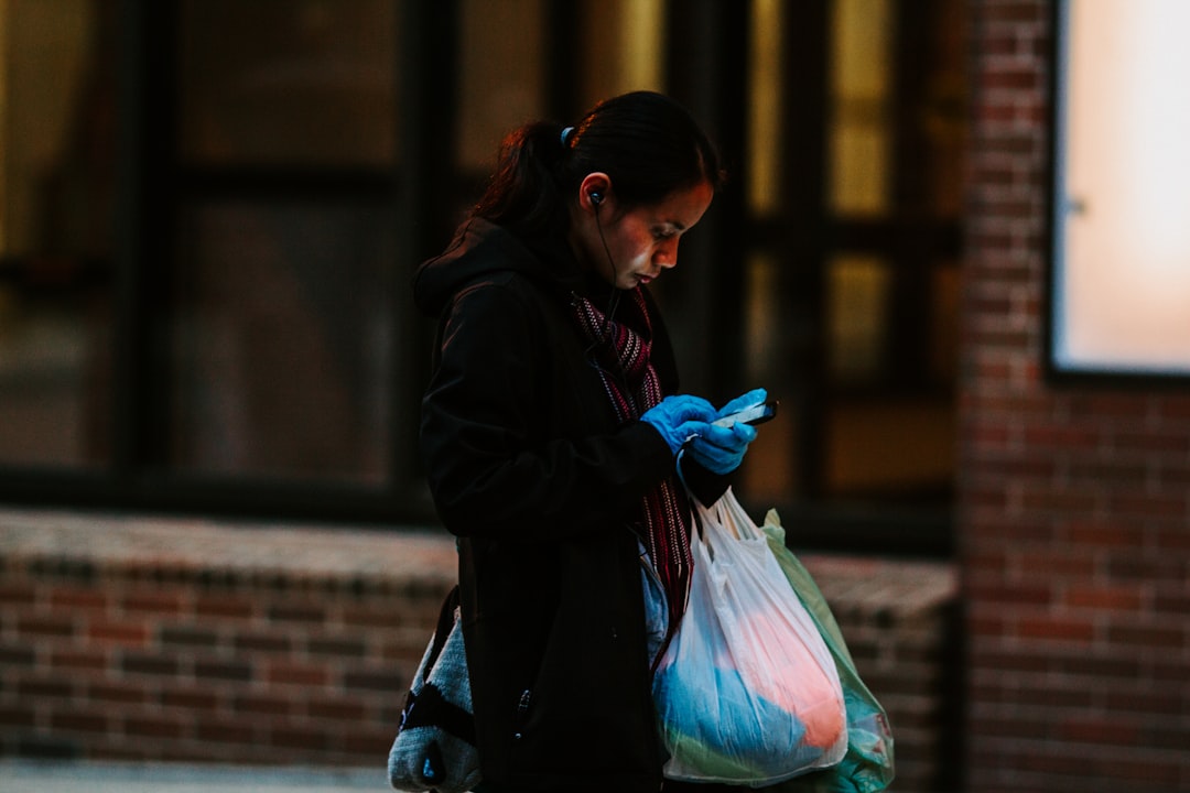 woman in black jacket holding pink plastic bag