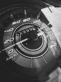 A close-up view of a car speedometer with markings indicating speeds from 0 to 160 km/h. The needle points to 0 and the odometer reading is 29999. The image is in black and white, giving it a classic appearance.