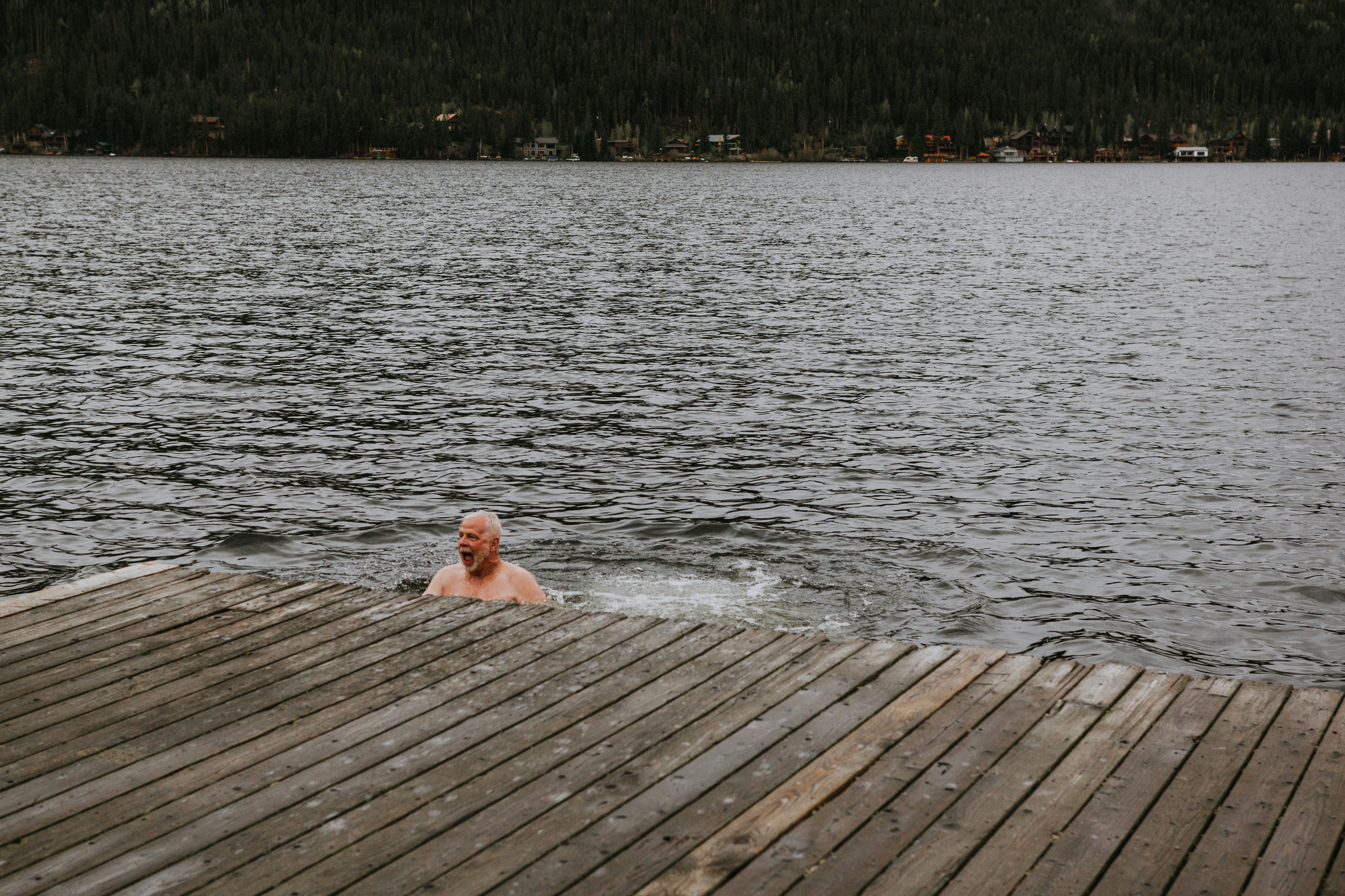 topless man lying on brown wooden dock during daytime