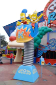 Families laughing together at a colorful theme park filled with rides and attractions.