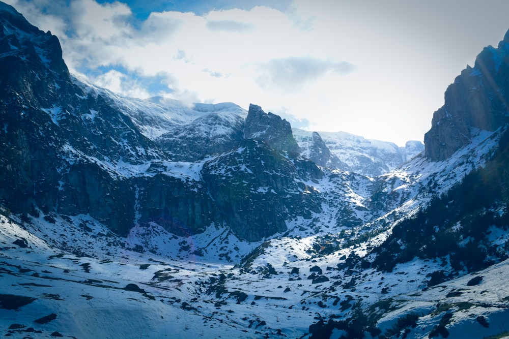 snow covered mountain under white clouds and blue sky during daytime