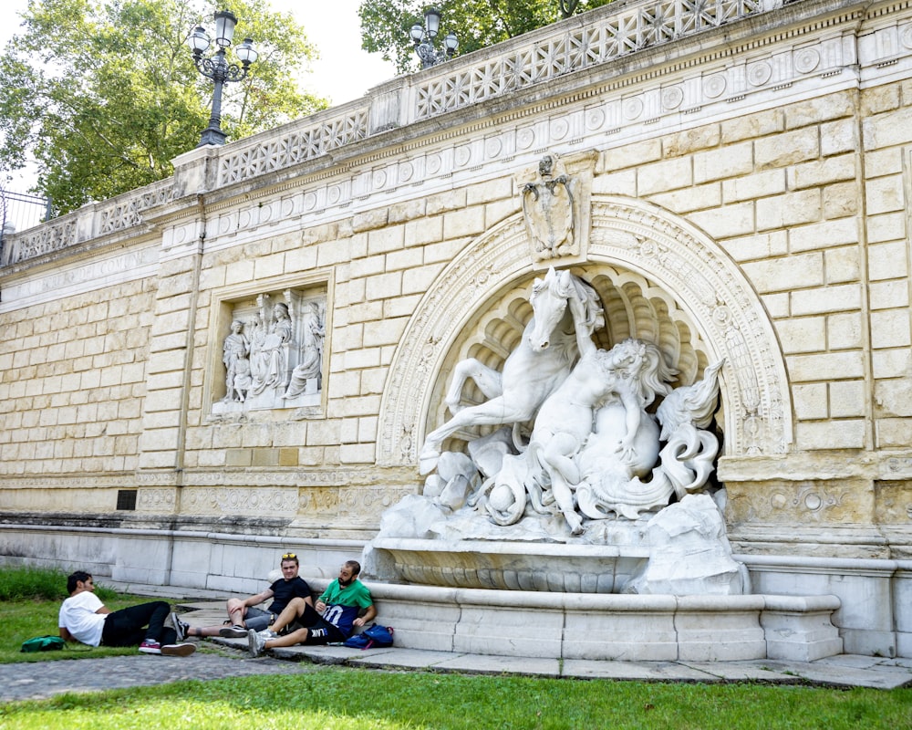 people sitting on green grass field near white concrete building during daytime