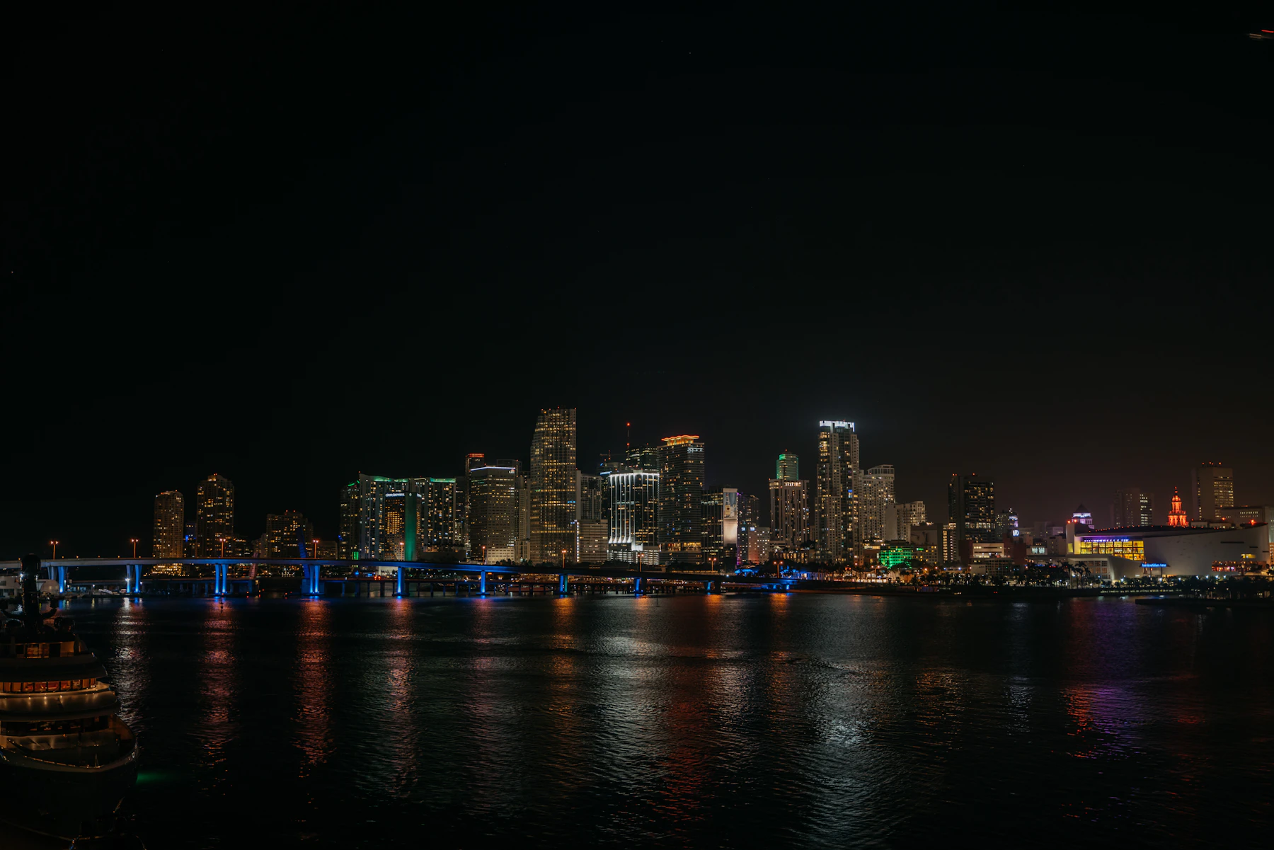 Downtown Miami skyline lit up at night, reflected in Biscayne Bay