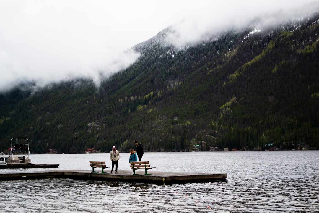 2 person sitting on brown wooden boat on lake during daytime