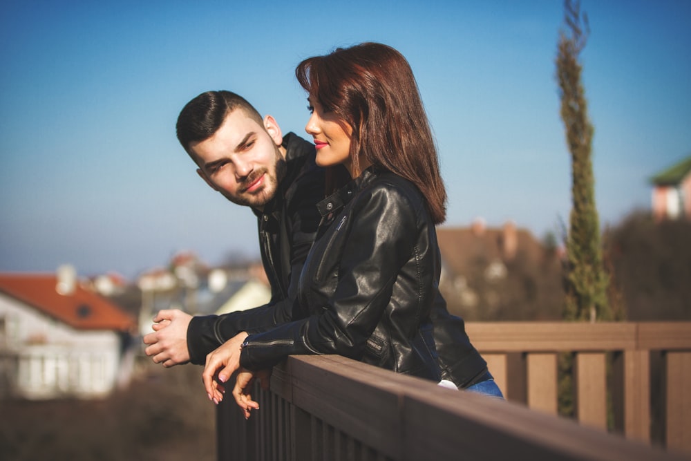 man in black leather jacket kissing woman in black leather jacket during daytime