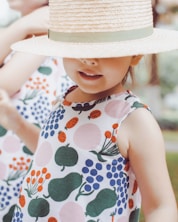 girl in white and green floral tank top wearing white sun hat