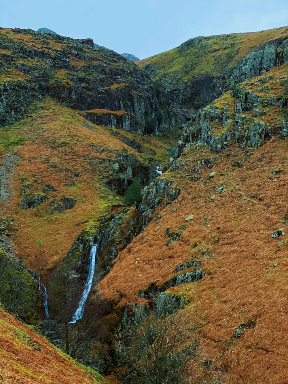 waterfalls in the middle of brown and green mountains