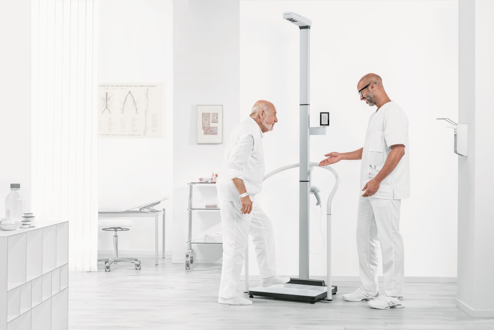 man in white t-shirt and white pants standing on black exercise equipment