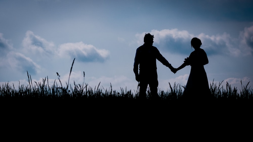 silhouette of man and woman holding hands during sunset