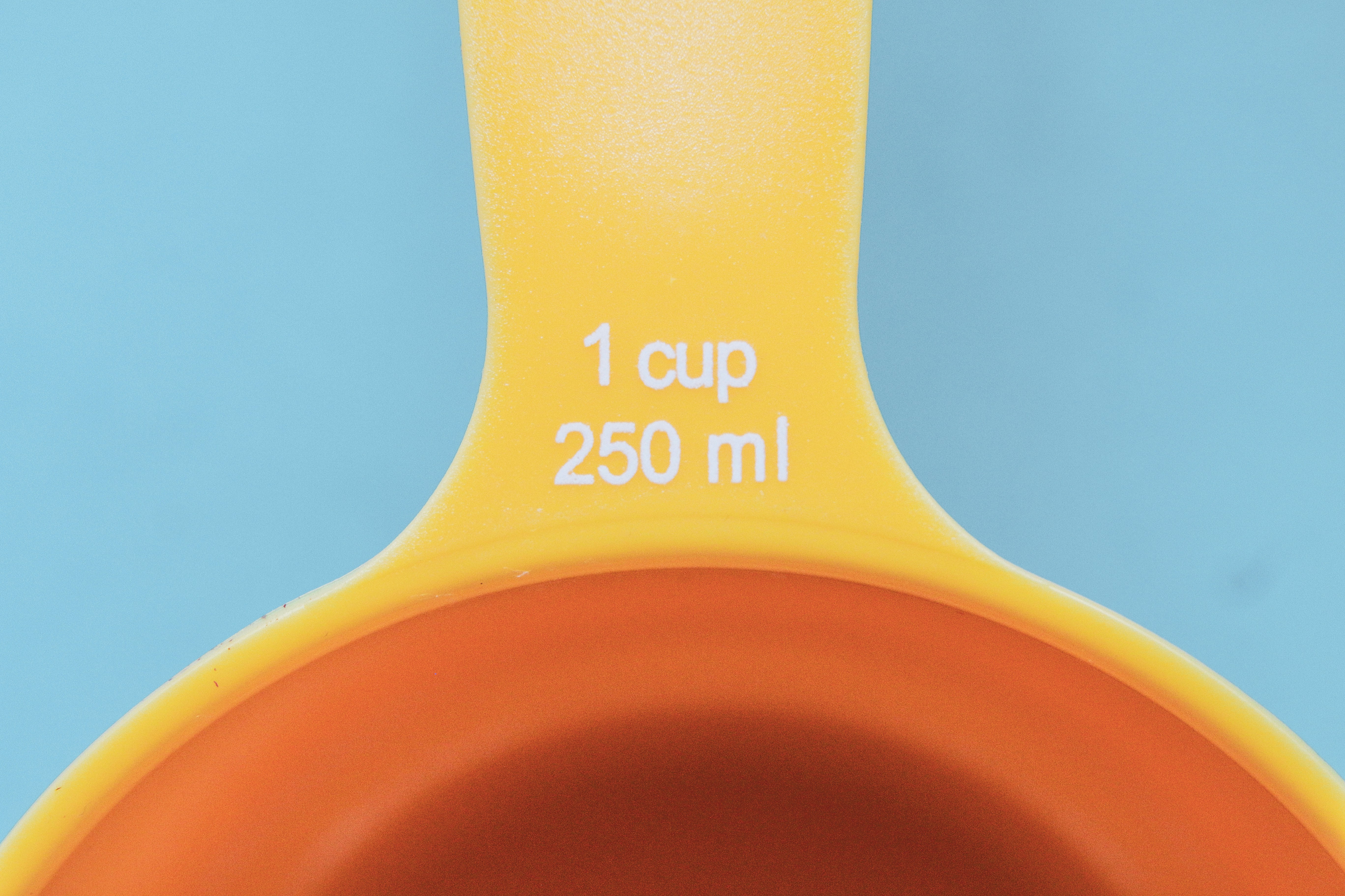 orange plastic measuring cup with yellow liquid