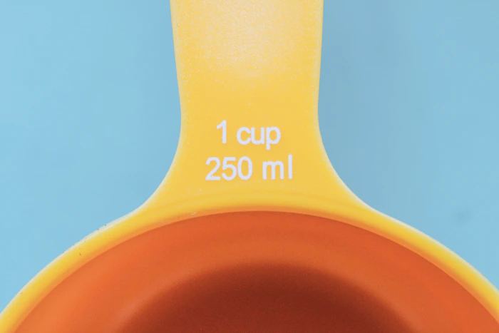 Assorted measuring cups and spoons laid out on a kitchen surface, used for cooking conversions