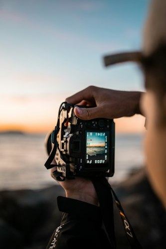 A traveler holding up a smartphone to photograph a scenic overlook at sunset