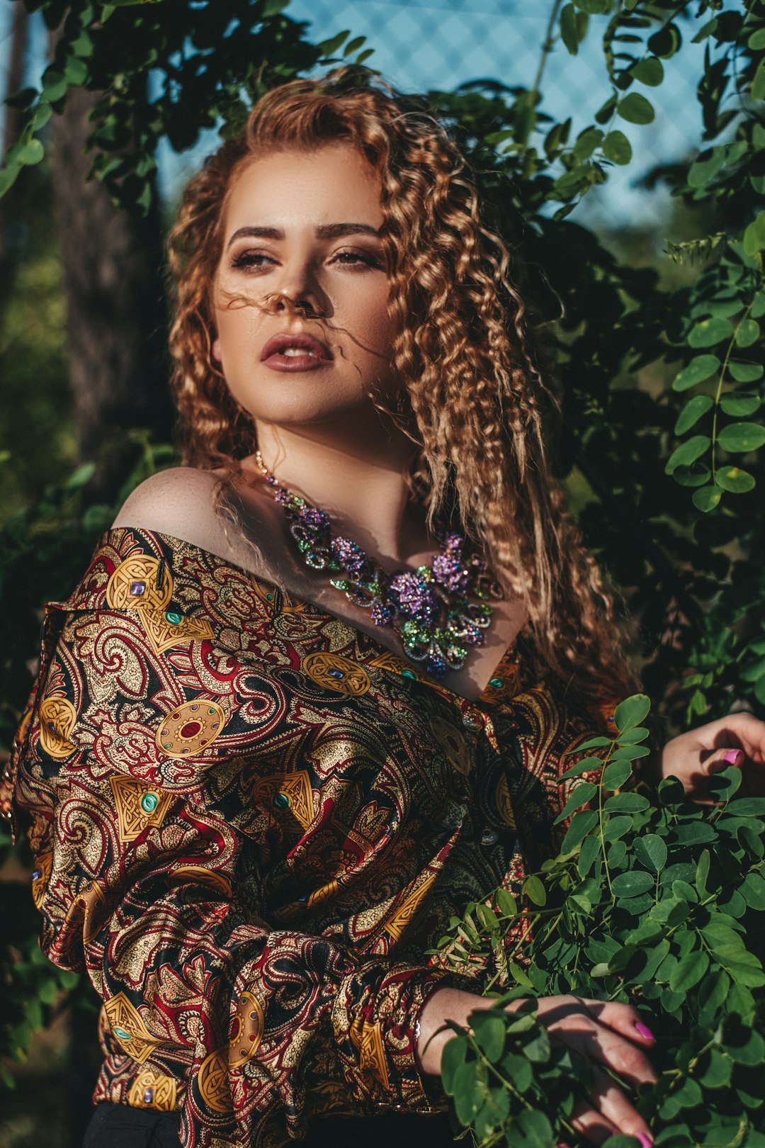 woman in brown and purple floral dress standing beside green plants during daytime