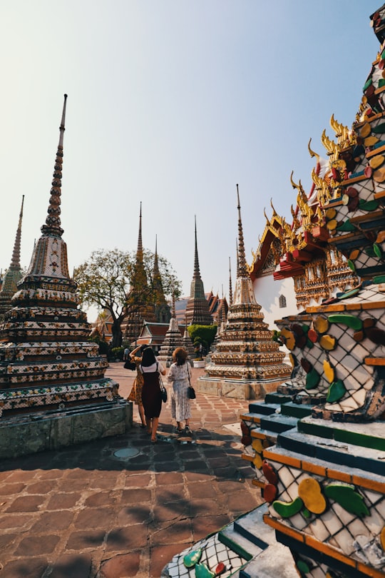 people walking near gold and white temple during daytime in Wat Pho Thailand