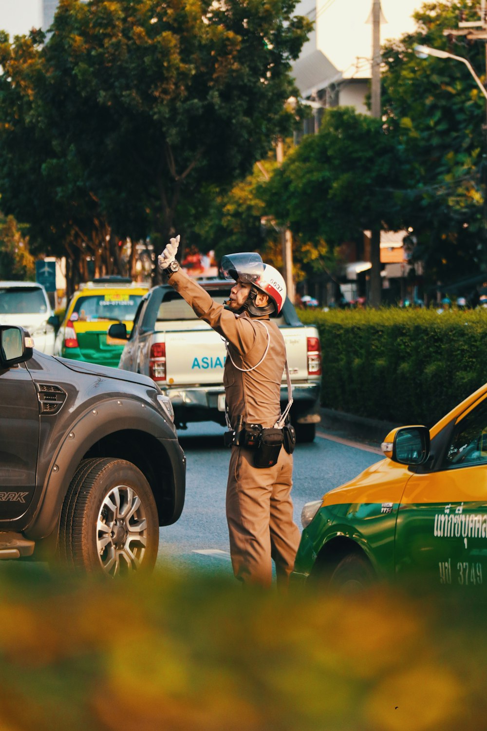 man in brown jacket and black pants standing beside green car during daytime