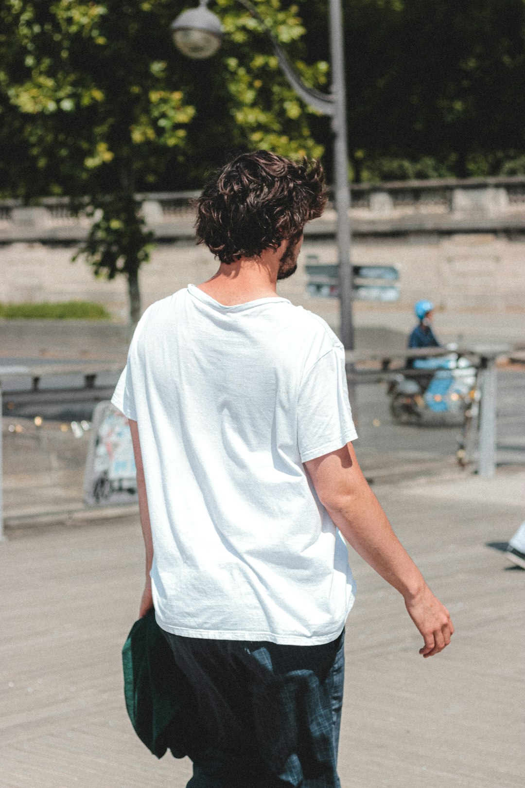 man in white crew neck t-shirt and green shorts standing on gray concrete road during