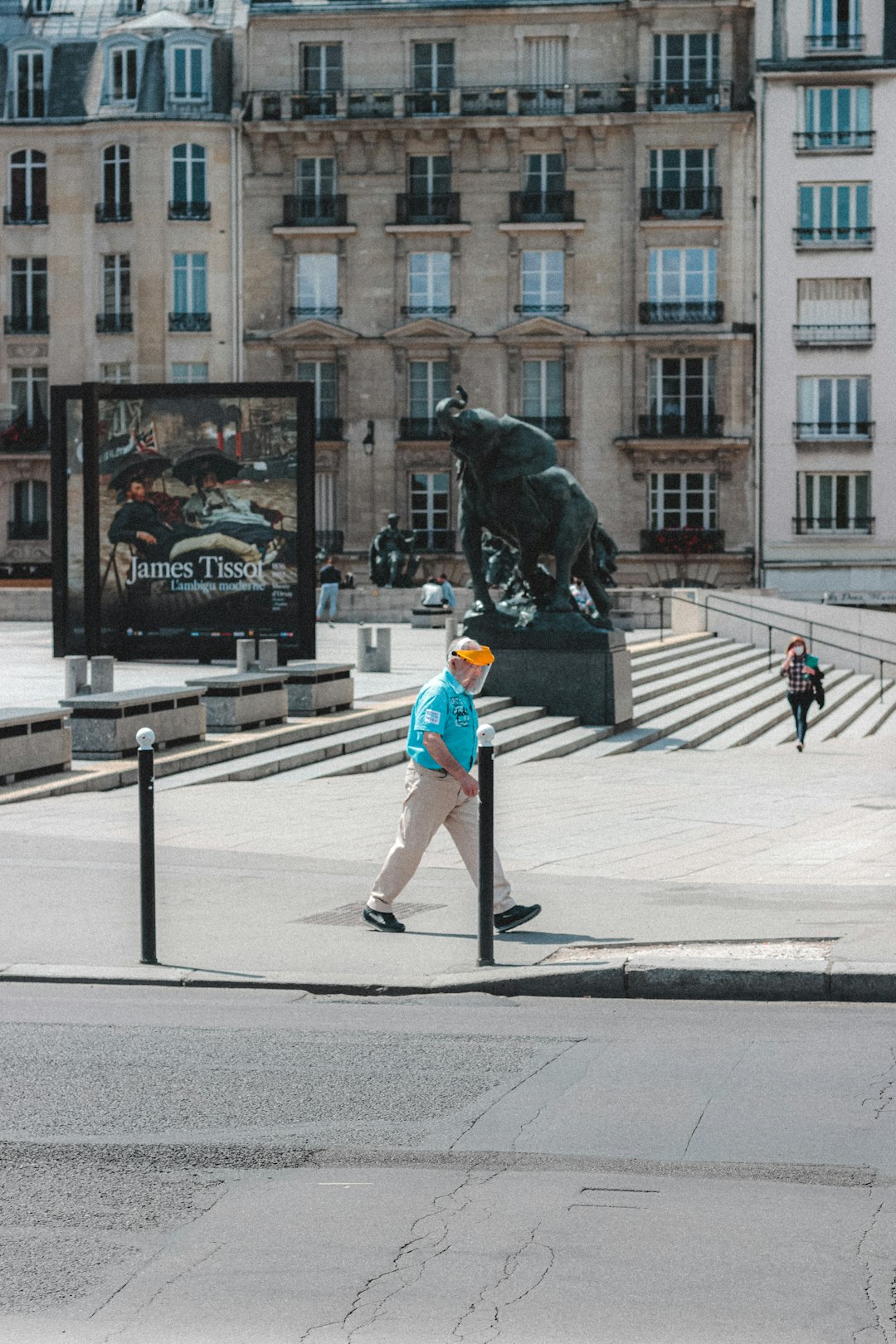 man in blue shirt and black pants standing on sidewalk during daytime