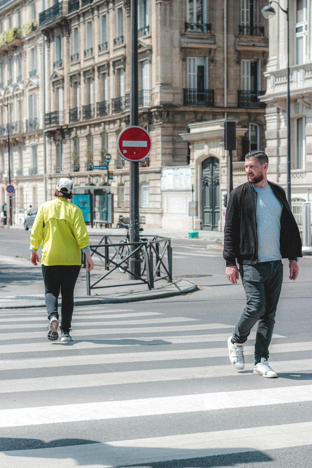 man in black jacket and blue denim jeans walking on pedestrian lane during daytime