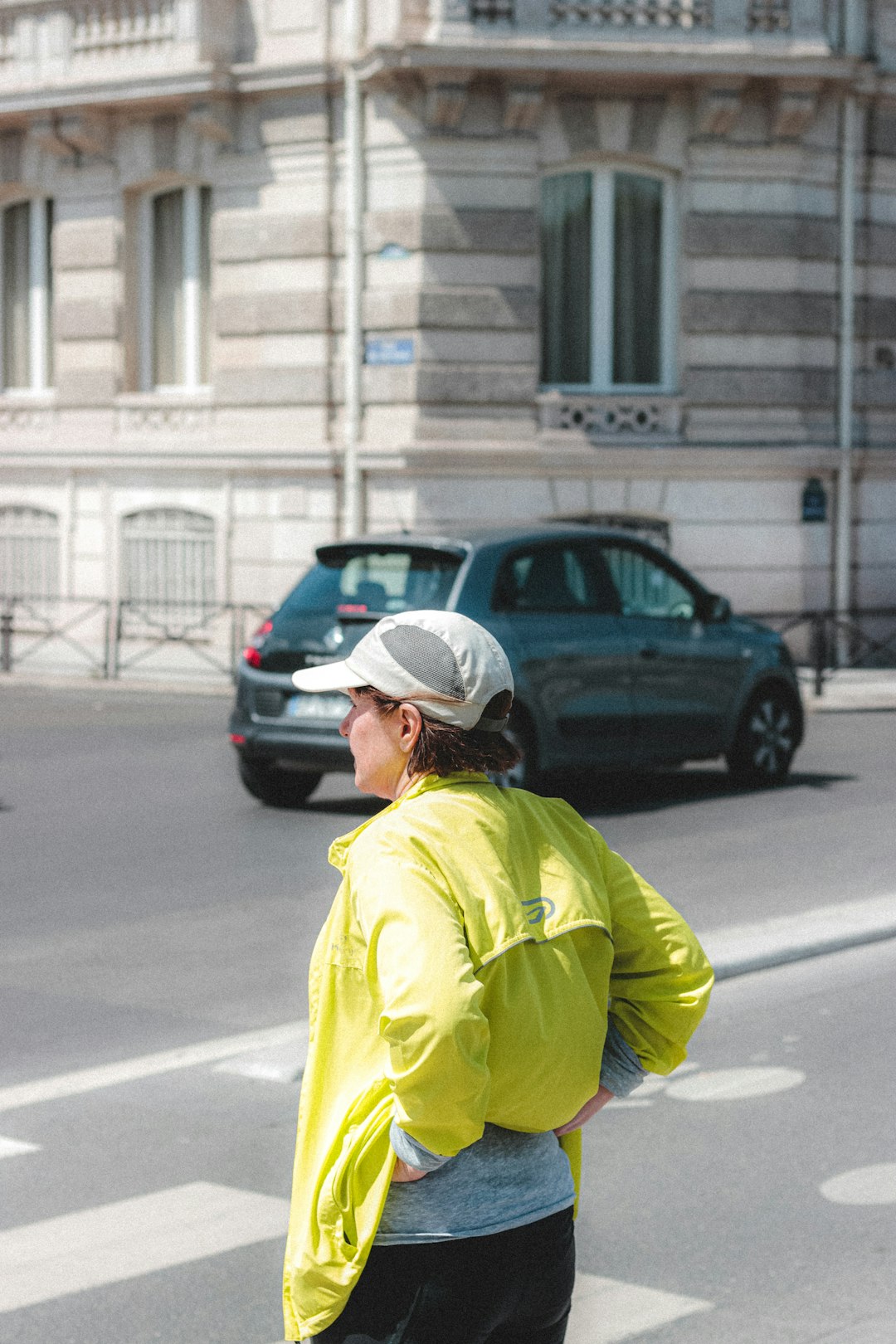 man in yellow jacket wearing white cap walking on street during daytime