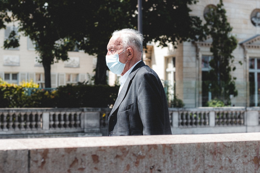 man in black suit jacket standing near green trees during daytime