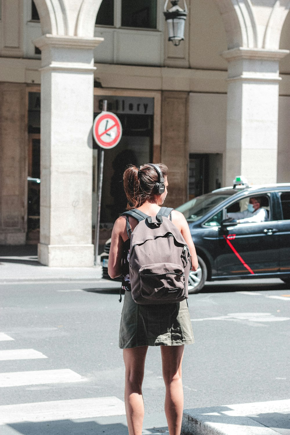 woman in black and red backpack standing on road during daytime