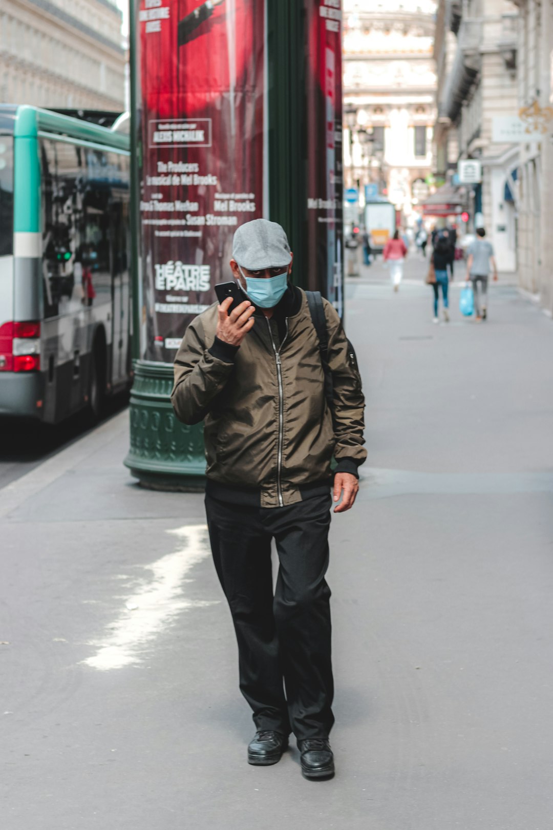 man in brown jacket and black pants standing on sidewalk during daytime