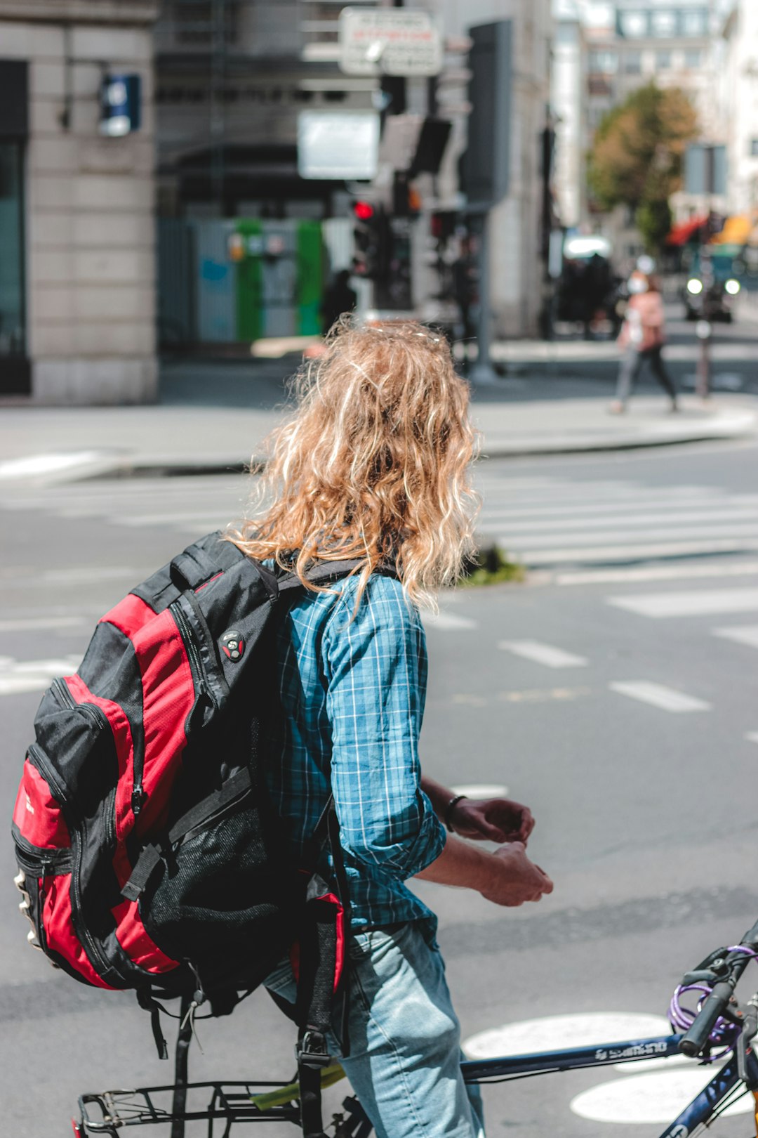 woman in blue jacket and black backpack walking on pedestrian lane during daytime