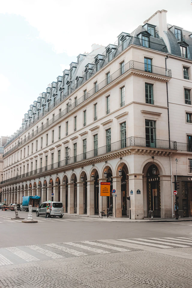 The uniform stone arcades of Rue de Rivoli with shopfronts beneath, at a quiet street corner