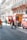 Several fire trucks and emergency personnel in uniforms are present on a city street lined with ornate buildings. A few pedestrians can also be seen walking nearby, and metal barricades are set up, suggesting a controlled or restricted area.