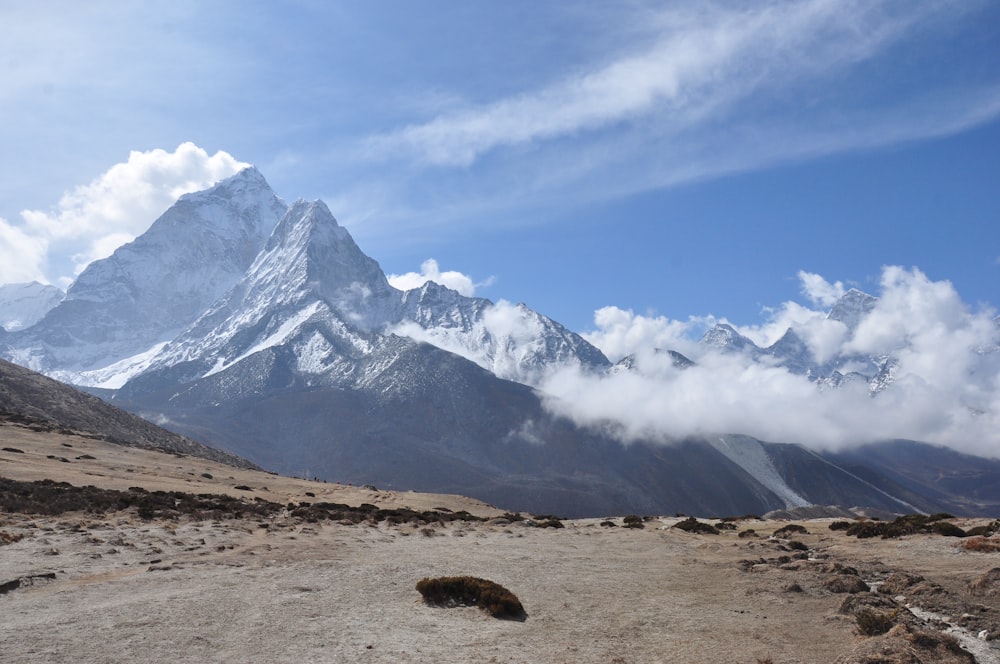 brown grass field near snow covered mountain during daytime