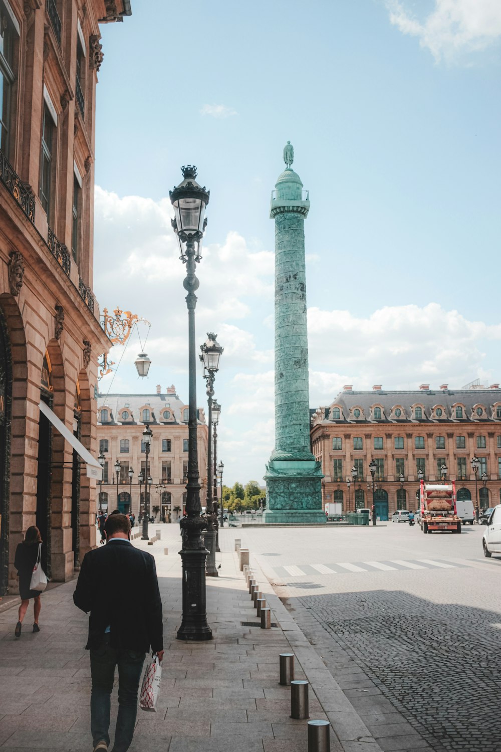 a man walking down a sidewalk next to a light pole