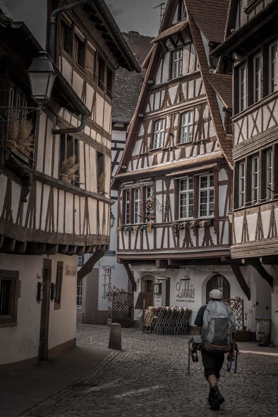 man in gray jacket standing beside brown concrete building during daytime in Maison des Tanneurs France