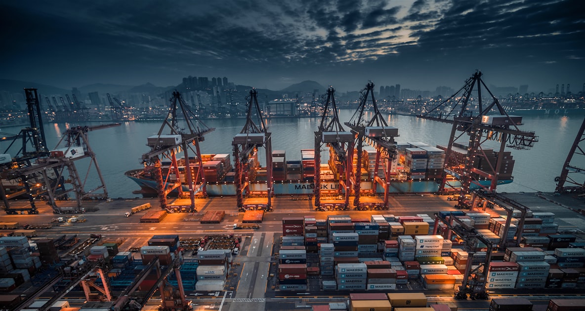 A red and black cargo container ship docked at port, illustrating ocean freight shipping for custom plush orders from China