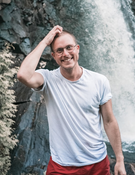 man in white crew neck t-shirt standing near gray rock in Saint-Côme Canada