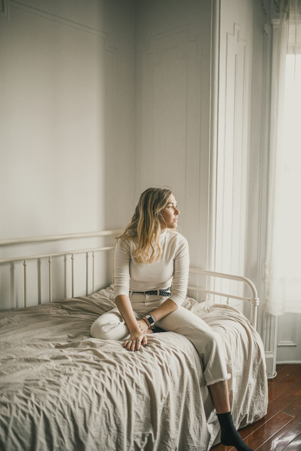 woman in white long sleeve shirt sitting on bed