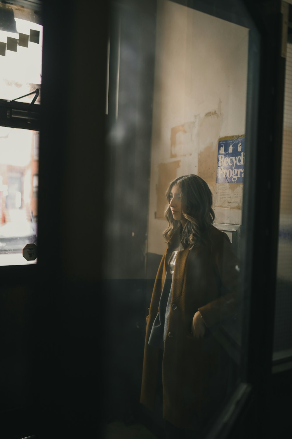woman in black jacket standing beside glass window