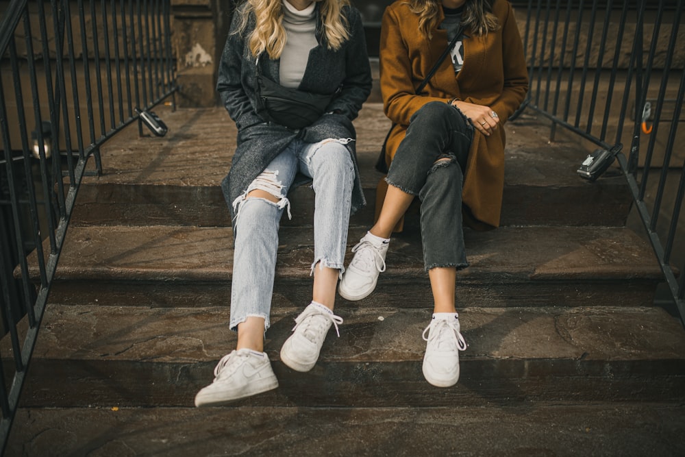 2 mulheres sentadas em escadas de madeira marrom