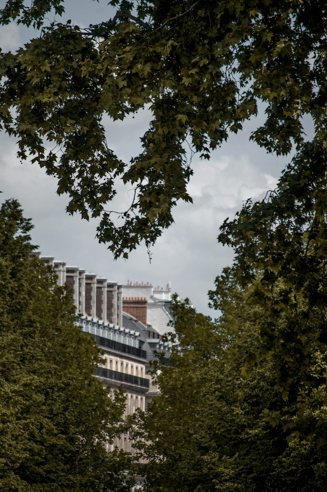 white concrete building near green trees under white clouds during daytime