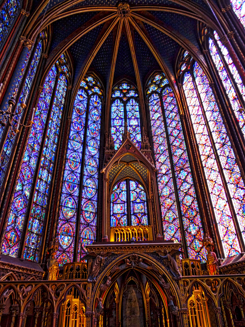 The image depicts a large, ornate cathedral with a high ceiling and numerous stained glass windows that fill the space with vibrant colors. The perspective is from below, looking up towards the towering structure. The cathedral's architecture features pointed arches and intricate designs, showcasing the craftsmanship of the era in which it was built.

The stained glass windows are particularly striking, with a variety of colors and patterns adorning each panel. These windows not only add to the visual appeal but also serve as a source of natural light within the cathedral, creating a serene atmosphere for worshipers.