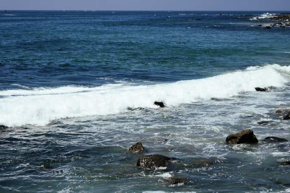 ocean waves crashing on rocks during daytime